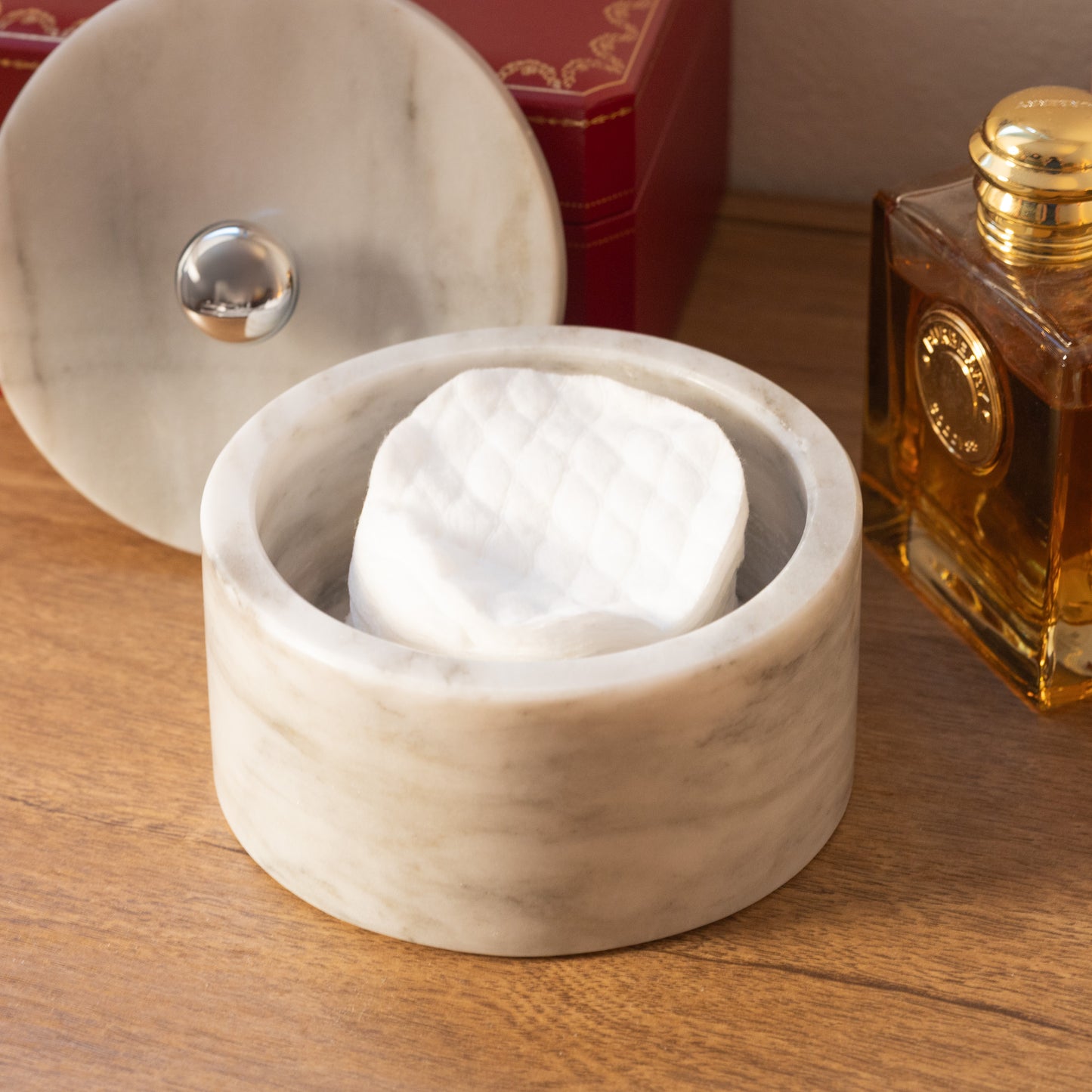 Die weiße Marmor-Schmuckschatulle von Marmonix, elegant auf einem Frisiertisch neben feinen Parfüms und Accessoires dekoriert.