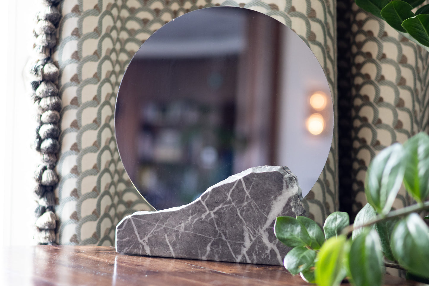 Eleganter Kosmetikspiegel mit grauem Marmorständer in einer hellen, luxuriösen Badezimmer- oder Schlafzimmerumgebung.