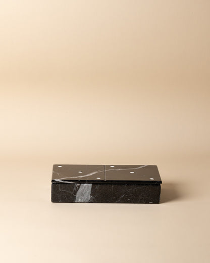 Black marble domino set on a beige background