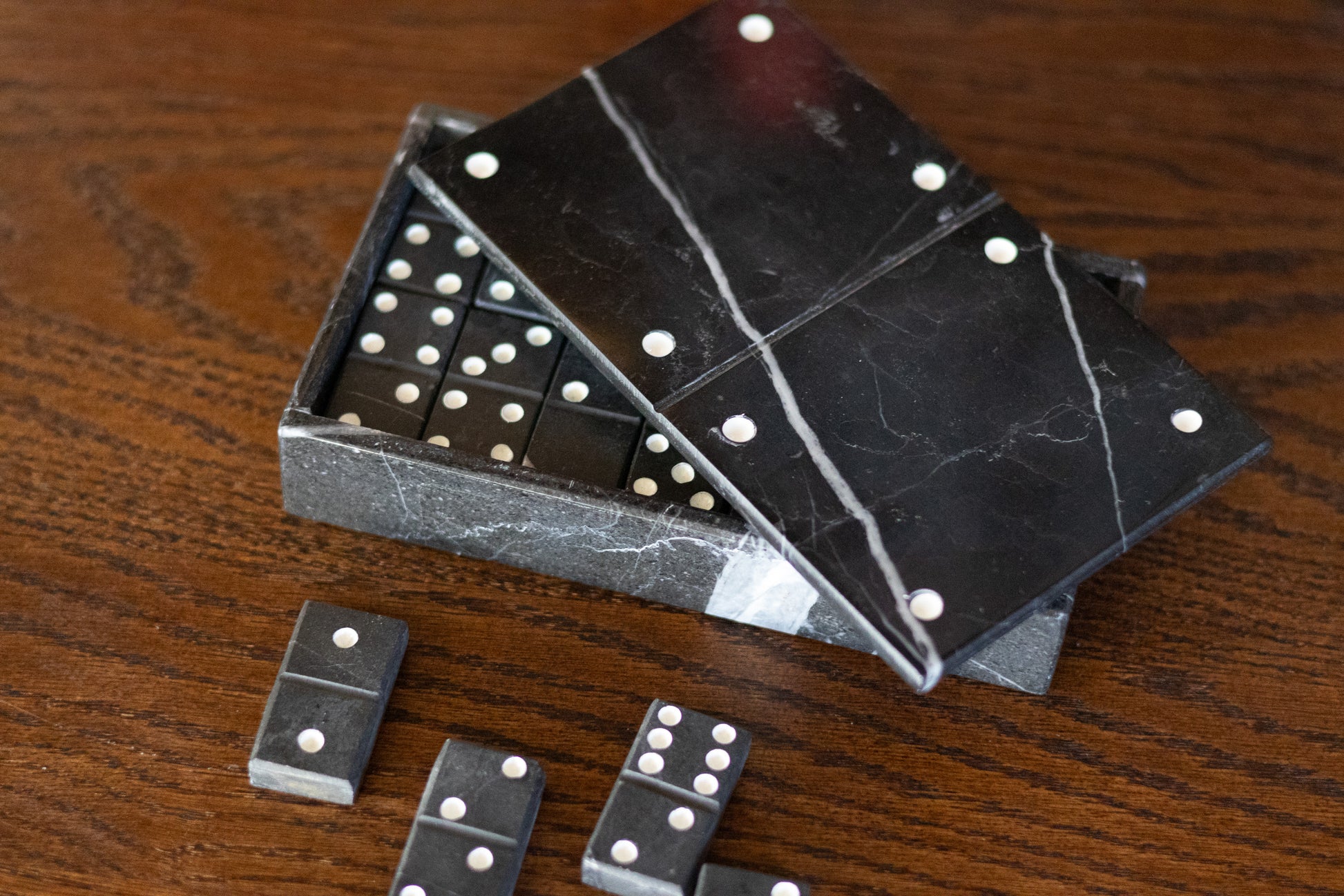 Das exklusive schwarze Marmor-Dominospiel von Marmonix, stilvoll arrangiert auf einem hochwertigen Holztisch für einen edlen Spieleabend im modern eingerichteten Wohnbereich.