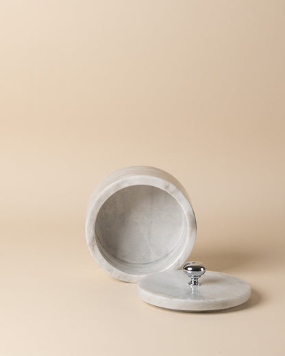 Marble-textured cylindrical container with a silver knob on a beige background