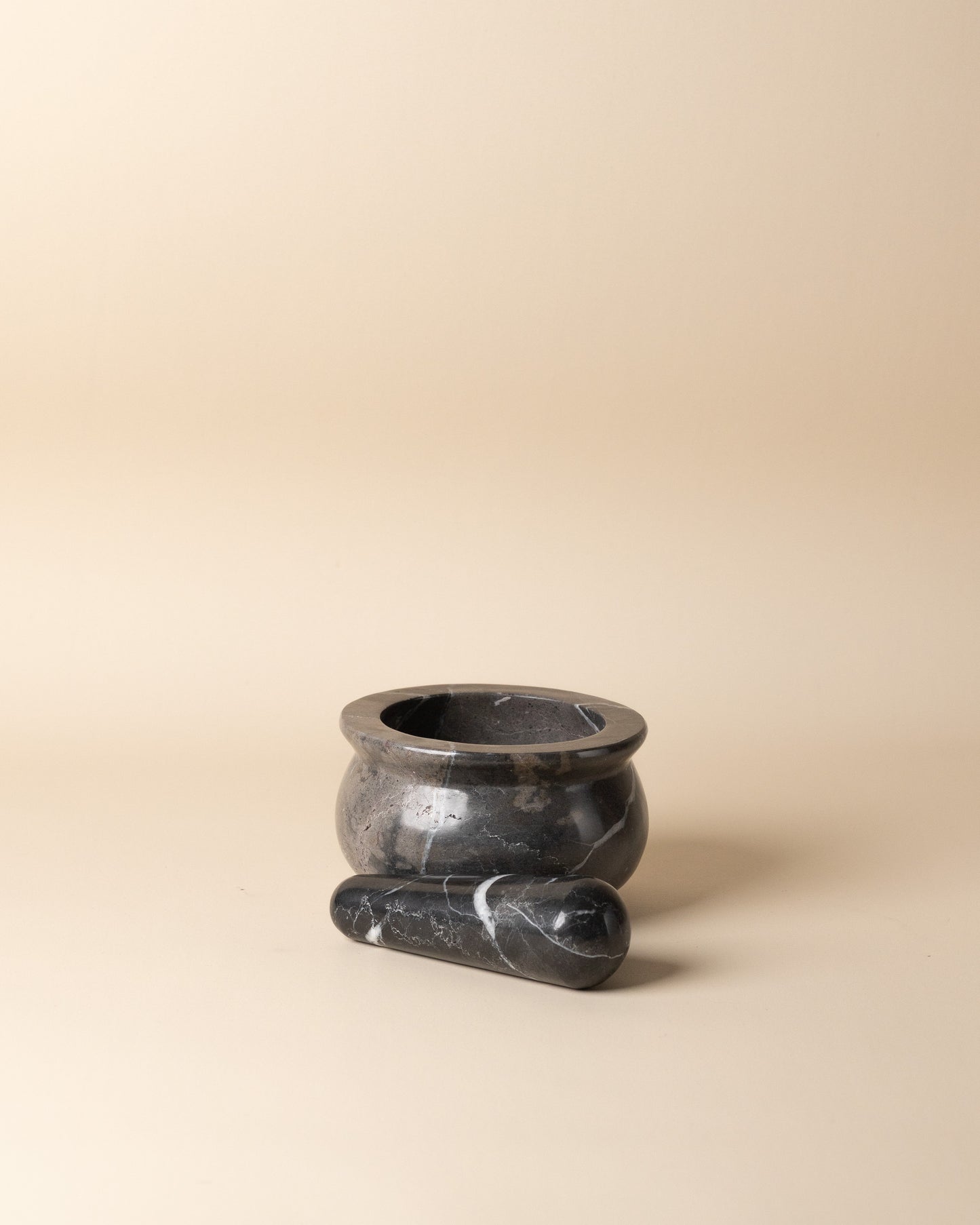 Black stone mortar and pestle on a beige background
