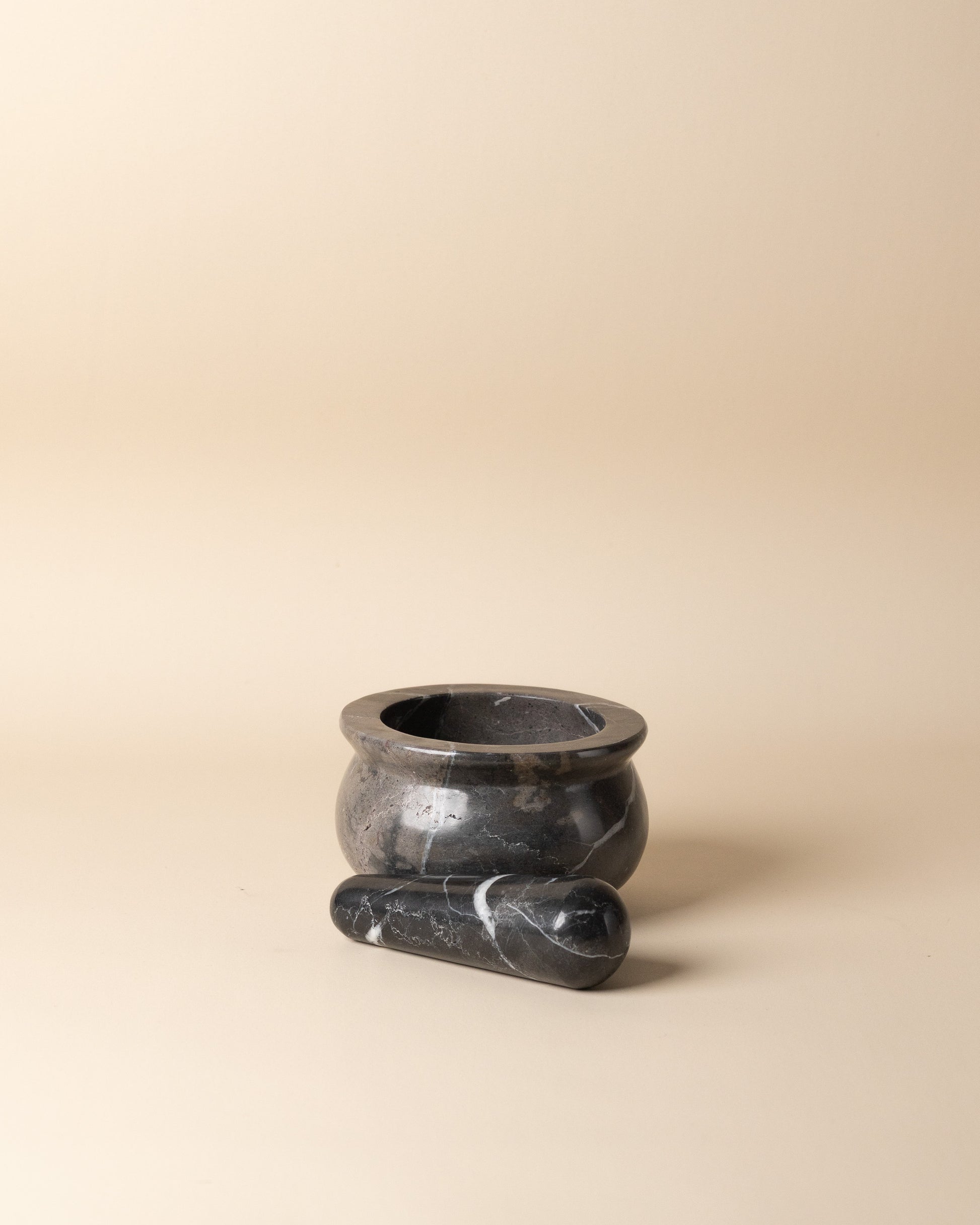 Black stone mortar and pestle on a beige background