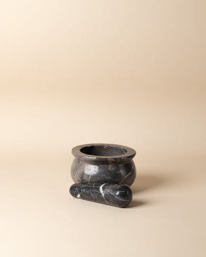 Black stone mortar and pestle on a beige background