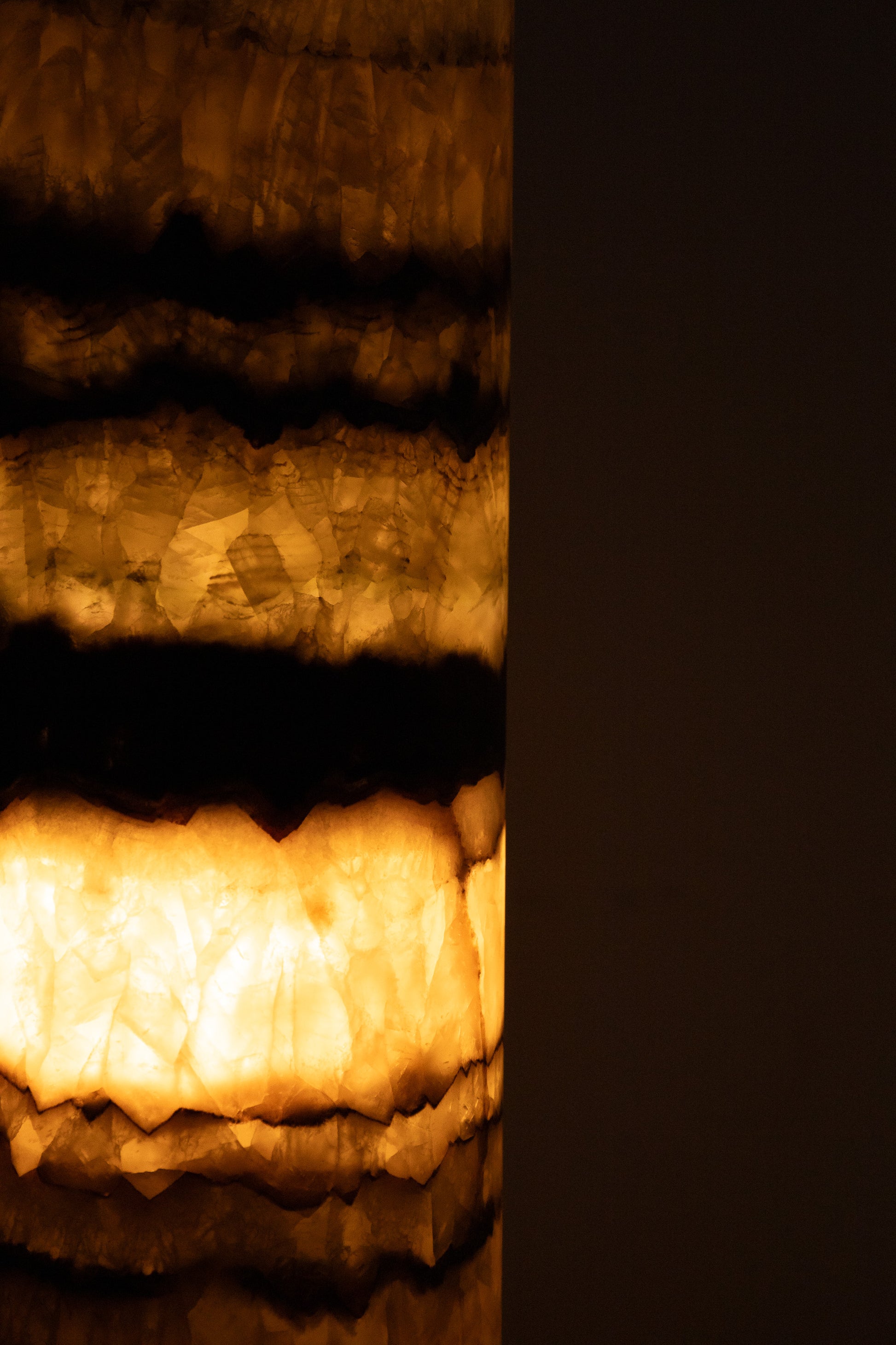 Stimmungsvolles Lifestyle-Bild der 35 cm Regenbogen-Onyx-Lampe von Marmonix, die warmes, gemütliches Licht in den Raum wirft.