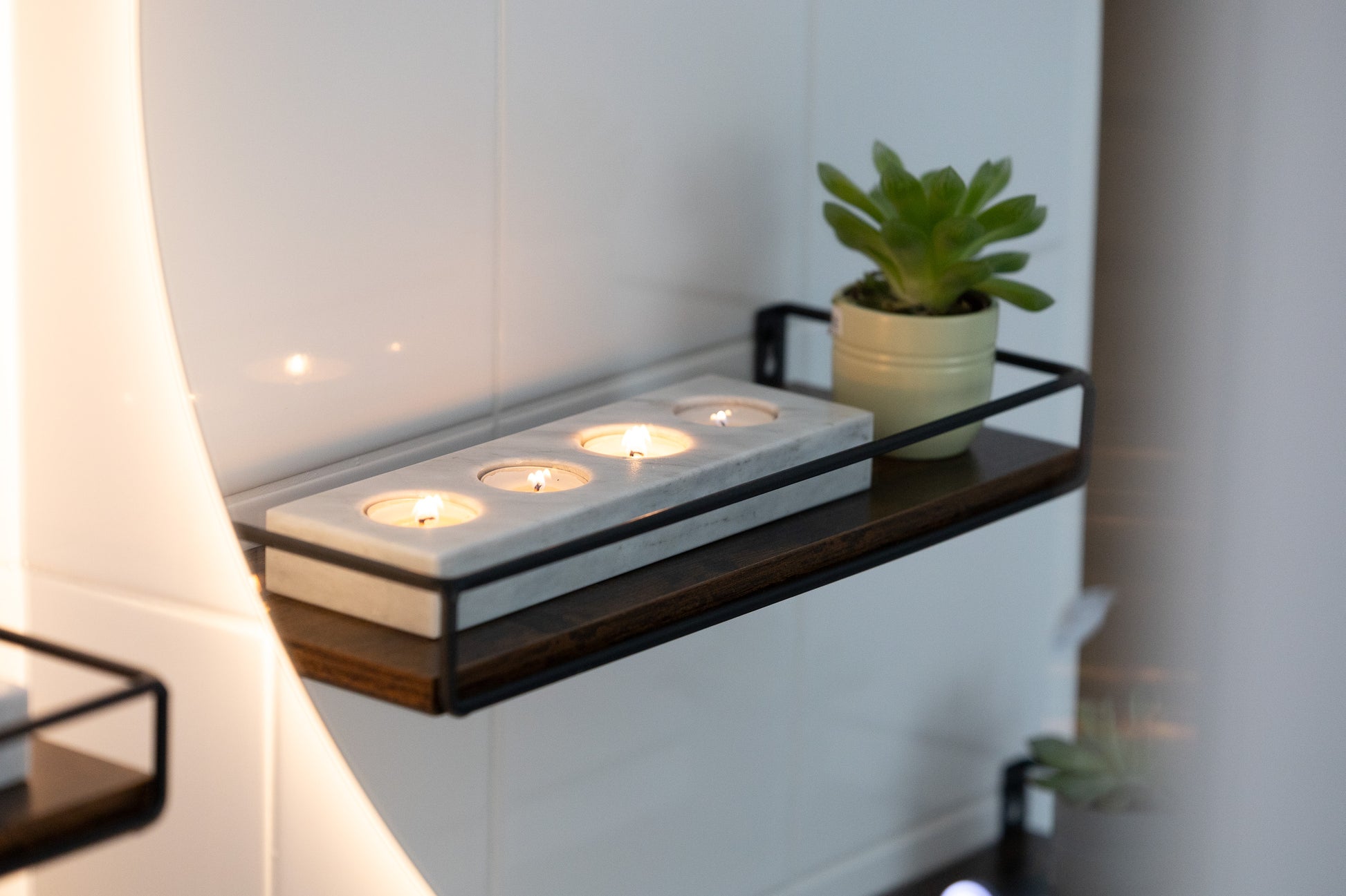 Das lange weiße Marmor-Teelichter-Centerpiece von Marmonix, stimmungsvoll erleuchtet auf einer festlichen Sideboard im Badezimmer.