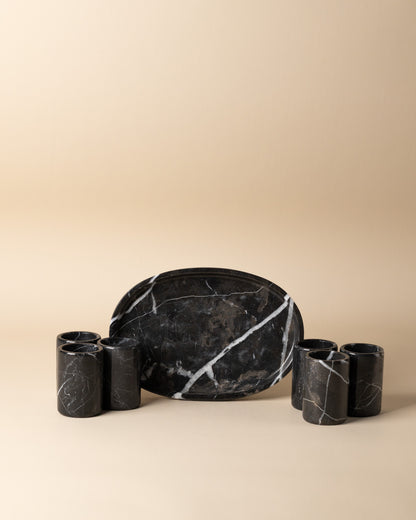 Black marble serving platter with six tequila shots on a beige background
