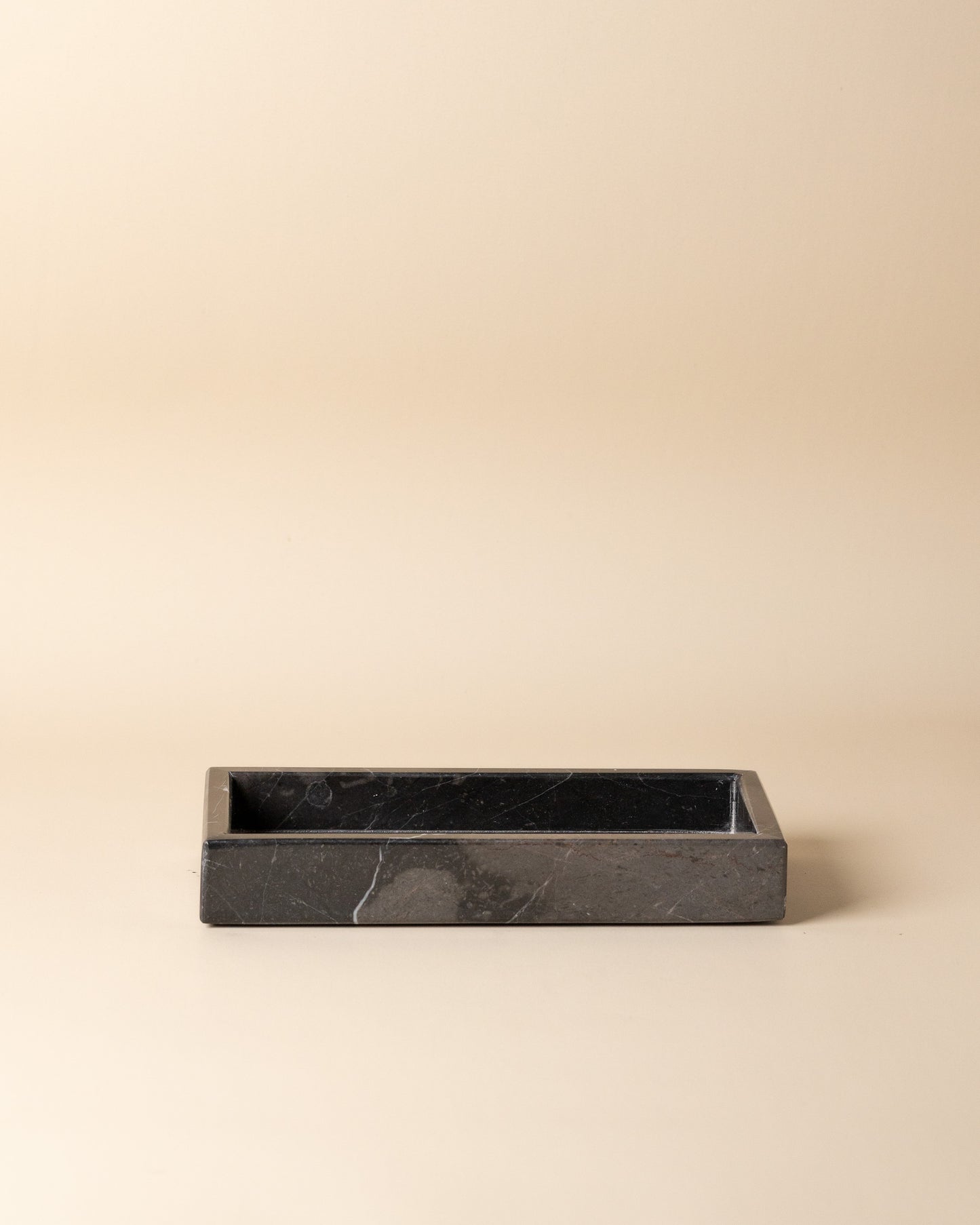 Black rectangular marble tray on a beige background