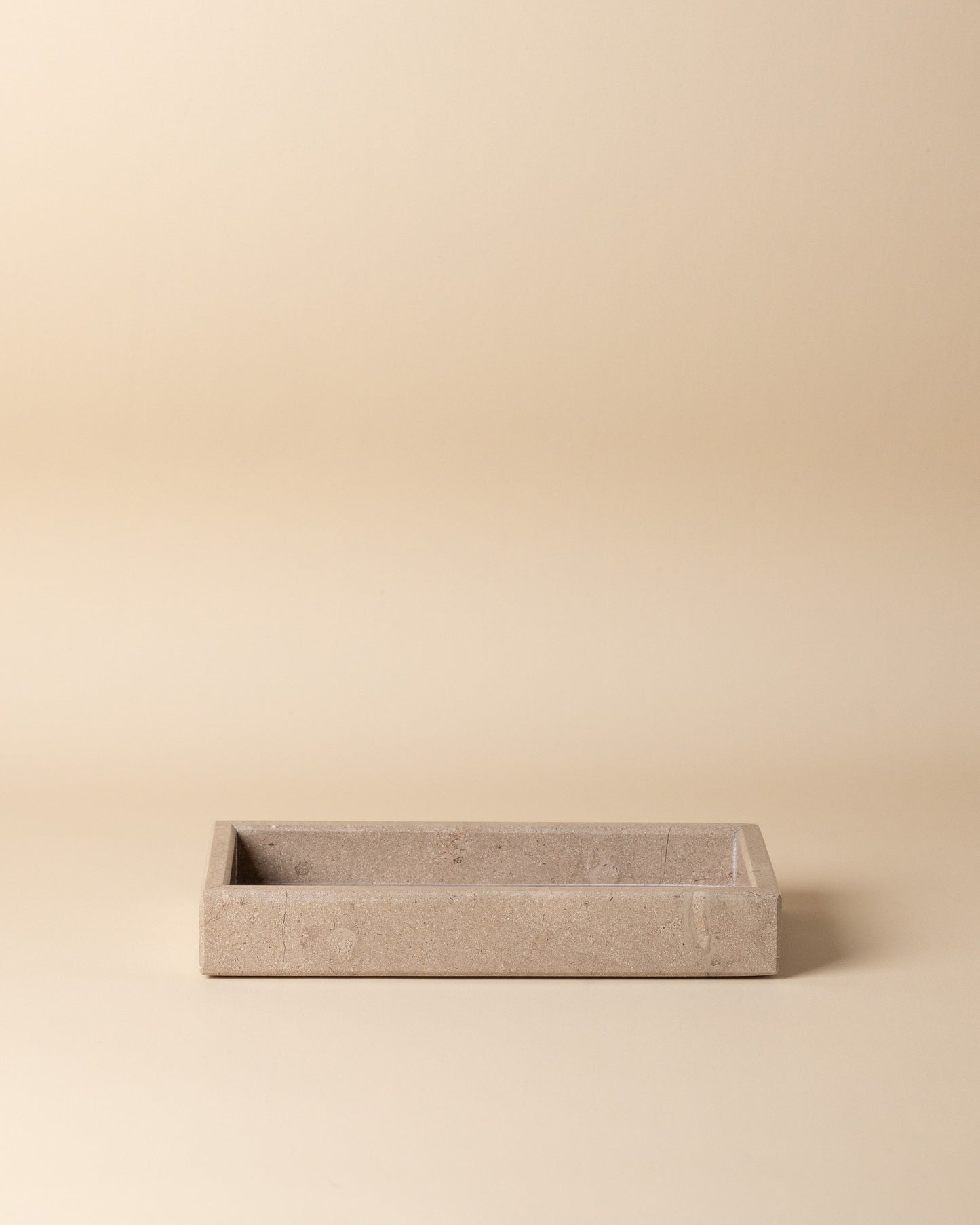 Rectangular travertine stone tray on a beige background