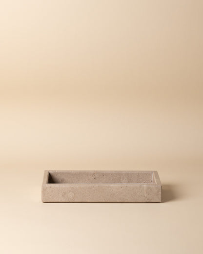 Rectangular travertine stone tray on a beige background