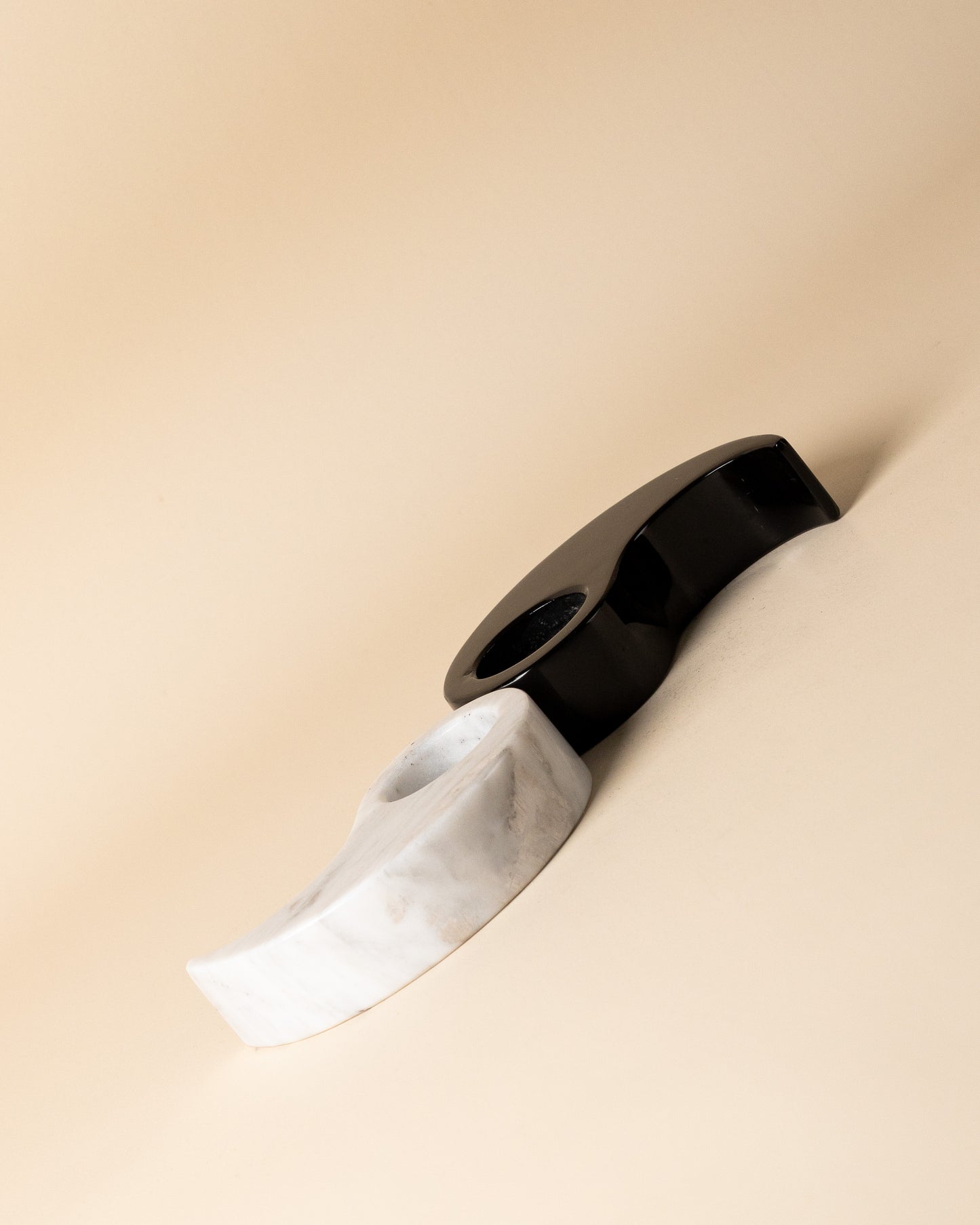 Ansicht des geöffneten Yin-Yang-Kerzenhalter-Sets von Marmonix, um die skulpturalen, geschwungenen Kurven und den starken Farbkontrast der einzelnen Natursteinstücke kunstvoll hervorzuheben.